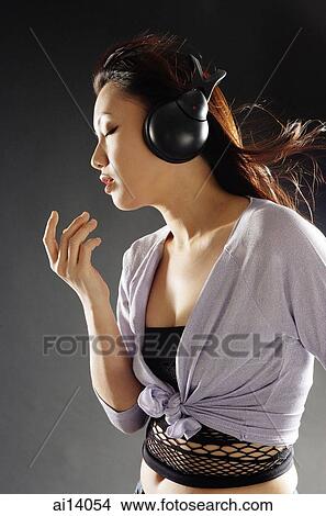 Young woman with headphones on, sideview View Large Photo Image Picture - Young woman with headphones on, sideview. Fotosearch
