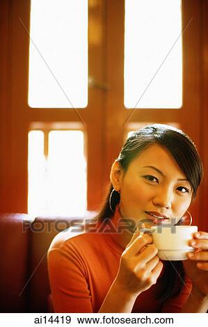 Stock Photo - Young woman with teacup, looking at camera. Fotosearch