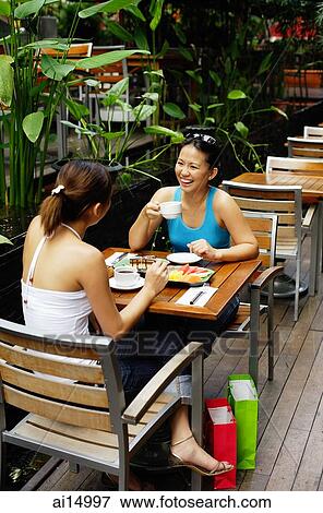 Young women at cafe, eating and drinking View Large Photo Image Stock Photo - Young women at cafe, eating and drinking. Fotosearch