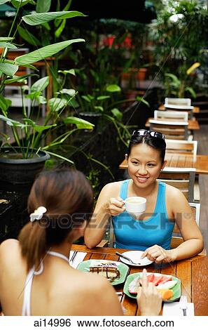 Young women at cafe, eating and drinking View Large Photo Image Stock Photograph - Young women at cafe, eating and drinking. Fotosearch