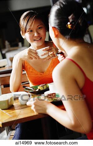 Young women at cafe, having coffee, over the shoulder view View Large Photo Image Stock Photo - Young women at cafe, having coffee, over the shoulder view. Fotosearch