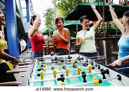 Stock Image - Young women celebrating winning a game of foosball. Fotosearch