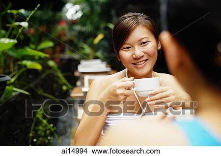 Young women having coffee at cafe, over the shoulder view View Large Photo Image Picture - Young women having coffee at cafe, over the shoulder view. Fotosearch