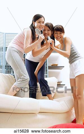 Stock Photo - Young women, holding hairbrushes, smiling at camera. Fotosearch