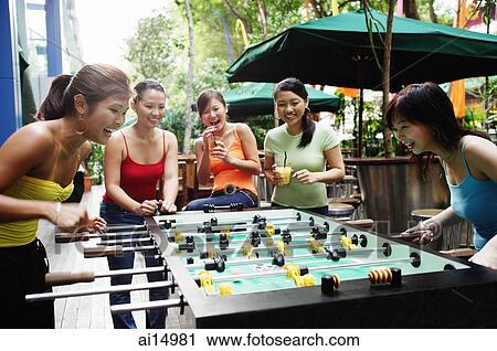 Stock Image - Young women playing foosball. Fotosearch