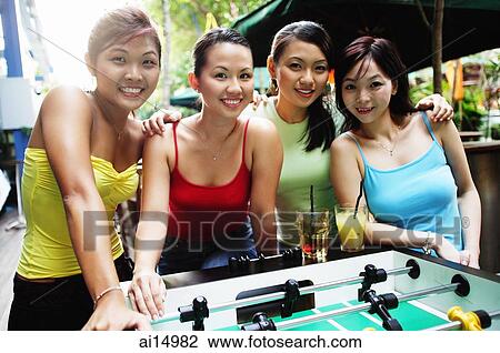Young women posing next to foosball table View Large Photo Image Stock Image - Young women posing next to foosball table. Fotosearch