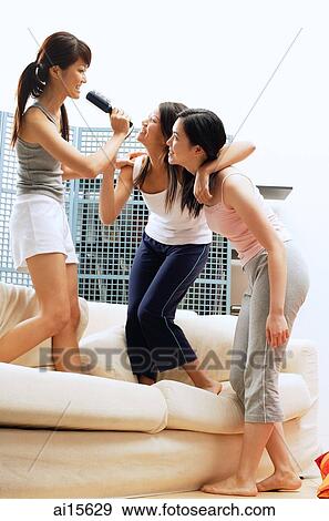 Stock Photo - Young women singing into hairbrushes. Fotosearch