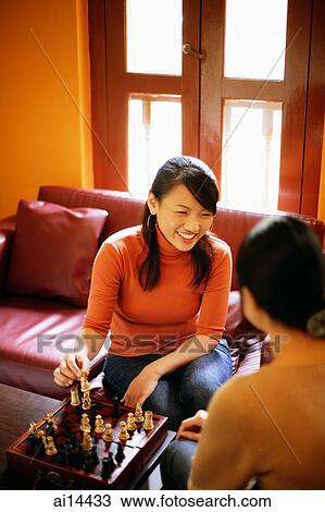 Young women sitting in living room, chess game on table View Large Photo Image Stock Image - Young women sitting in living room, chess game on table. Fotosearch