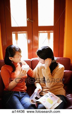 Young women sitting on sofa, talking View Large Photo Image Stock Photograph - Young women sitting on sofa, talking. Fotosearch