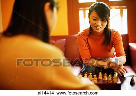 Picture - Young women sitting, playing chess. Fotosearch