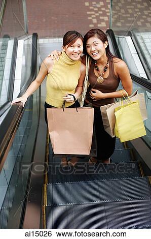 Young women, standing on escalator, looking up at camera View Large Photo Image Stock Photograph - Young women, standing on escalator, looking up at camera. Fotosearch