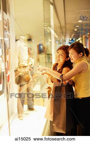 Young women, standing outside window display, looking in, pointing View Large Photo Image Stock Photography - Young women, standing outside window display, looking in, pointing. Fotosearch