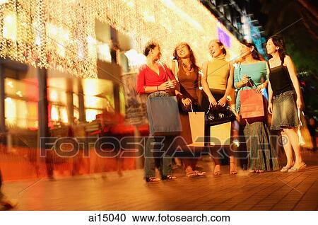 Young women standing side by side, in a row, carrying shopping bags View Large Photo Image Stock Image - Young women standing side by side, in a row, carrying shopping bags. Fotosearch