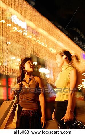 Young women walking side by side, carrying shopping bags View Large Photo Image Stock Photo - Young women walking side by side, carrying shopping bags. Fotosearch