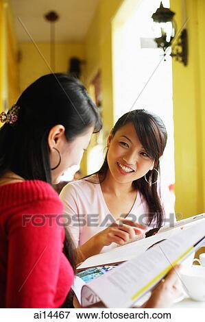 Young women with newspaper, smiling at each other View Large Photo Image Stock Photo - Young women with newspaper, smiling at each other. Fotosearch
