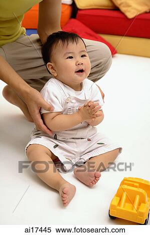 Baby boy sitting on floor, father supporting him View Large Photo Image Stock Photography - Baby boy sitting on floor, father supporting him . Fotosearch