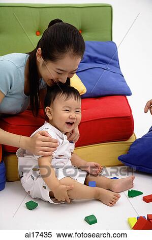 Baby boy sitting on floor, mother kissing him on top of head View Large Photo Image Stock Photography - Baby boy sitting on floor, mother kissing him on top of head . Fotosearch