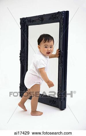 Baby boy standing next to mirror, smiling at camera View Large Photo Image Stock Photo - Baby boy standing next to mirror, smiling at camera . Fotosearch