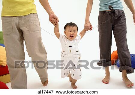Stock Photo - Baby boy walking between his parents . Fotosearch