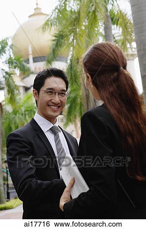 Businessman and businesswoman shaking hands, mosque in the background View Large Photo Image Stock Photograph - Businessman and businesswoman shaking hands, mosque in the background . Fotosearch