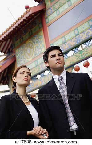 Stock Photo - Businessman and businesswoman standing in front of temple gate . Fotosearch