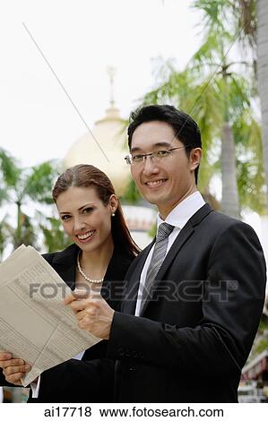 Businessman and businesswoman with newspaper, smiling at camera View Large Photo Image Stock Photo - Businessman and businesswoman with newspaper, smiling at camera. Fotosearch