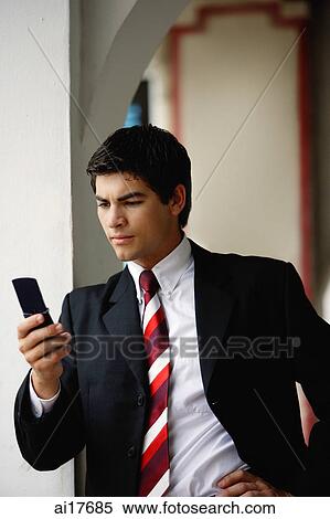 Businessman looking at mobile phone, leaning on wall View Large Photo Image Stock Photography - Businessman looking at mobile phone, leaning on wall . Fotosearch