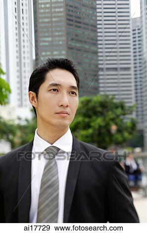 Businessman looking away, buildings in the background View Large Photo Image Stock Photo - Businessman looking away, buildings in the background . Fotosearch