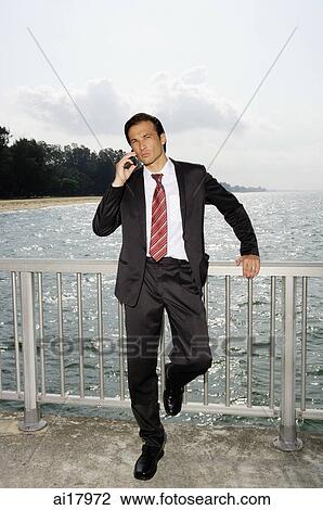 Businessman on boardwalk, using mobile phone View Large Photo Image Stock Image - Businessman on boardwalk, using mobile phone . Fotosearch