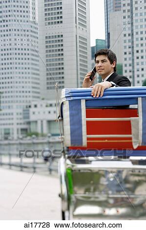 Businessman sitting in trishaw, using mobile phone, buildings in the background View Large Photo Image Stock Photo - Businessman sitting in trishaw, using mobile phone, buildings in the background . Fotosearch
