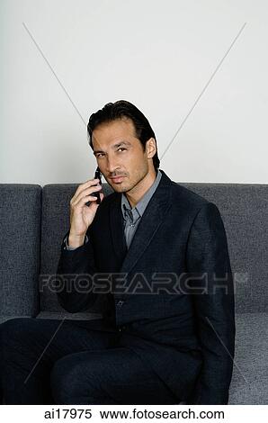 Businessman sitting on sofa, using mobile phone View Large Photo Image Stock Photography - Businessman sitting on sofa, using mobile phone . Fotosearch