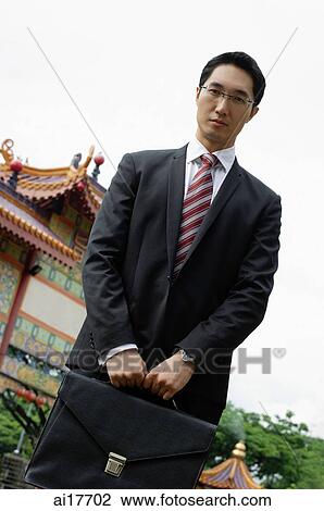 Businessman standing in front of Chinese temple, carrying briefcase View Large Photo Image Stock Image - Businessman standing in front of Chinese temple, carrying briefcase. Fotosearch