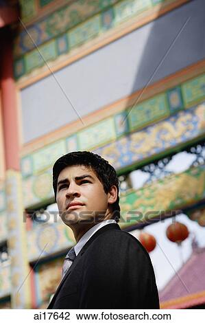 Businessman standing in front of temple gate, looking away View Large Photo Image Stock Image - Businessman standing in front of temple gate, looking away. Fotosearch