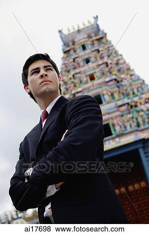 Businessman standing with arms crossed, Hindu temple in the background View Large Photo Image Stock Photo - Businessman standing with arms crossed, Hindu temple in the background . Fotosearch