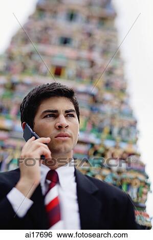 Businessman using mobile phone, Hindu temple in the background View Large Photo Image Stock Photograph - Businessman using mobile phone, Hindu temple in the background . Fotosearch