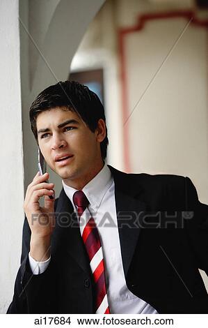 Businessman using mobile phone, leaning on wall View Large Photo Image Picture - Businessman using mobile phone, leaning on wall. Fotosearch