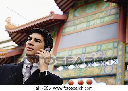 Businessman using mobile phone, standing in front of temple gate View Large Photo Image Stock Photography - Businessman using mobile phone, standing in front of temple gate . Fotosearch