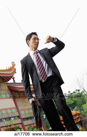 Businessman with briefcase, looking at watch View Large Photo Image Stock Photograph - Businessman with briefcase, looking at watch. Fotosearch