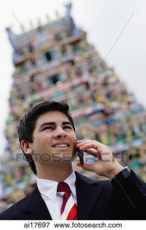 Businessman with mobile phone, Hindu temple in the background View Large Photo Image Stock Photo - Businessman with mobile phone, Hindu temple in the background . Fotosearch