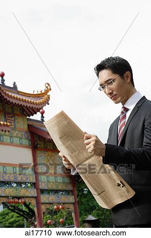 Businessman with newspaper, Chinese temple in the background View Large Photo Image Stock Image - Businessman with newspaper, Chinese temple in the background . Fotosearch