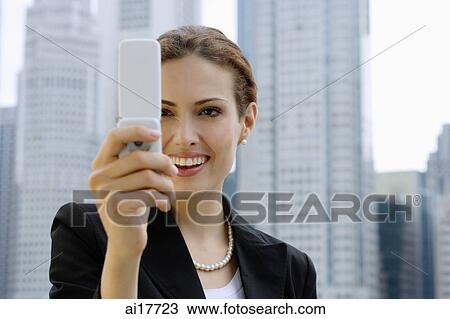 Stock Image - Businesswoman using mobile phone, photo messaging. Fotosearch