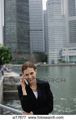 Businesswoman using mobile phone, river and buildings in the background View Large Photo Image Stock Photo - Businesswoman using mobile phone, river and buildings in the background . Fotosearch