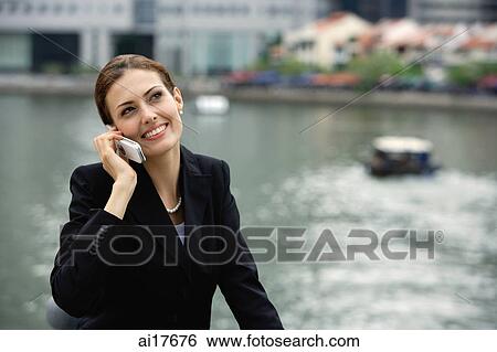 Businesswoman using mobile phone, river in the background View Large Photo Image Stock Photograph - Businesswoman using mobile phone, river in the background . Fotosearch