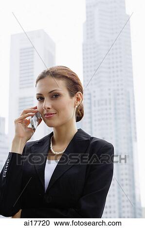 Businesswoman using mobile phone, buildings in the background View Large Photo Image Stock Image - Businesswoman using mobile phone, buildings in the background . Fotosearch