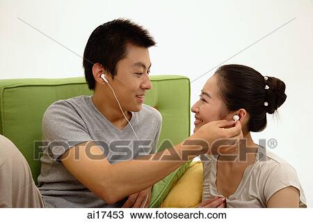 Couple face to face, listening to music through earphones View Large Photo Image Stock Image - Couple face to face, listening to music through earphones . Fotosearch