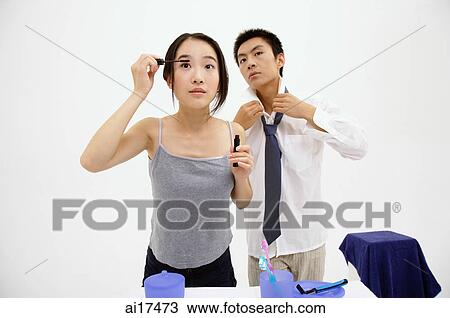 Couple getting ready, woman applying mascara, man adjusting tie View Large Photo Image Stock Image - Couple getting ready, woman applying mascara, man adjusting tie . Fotosearch