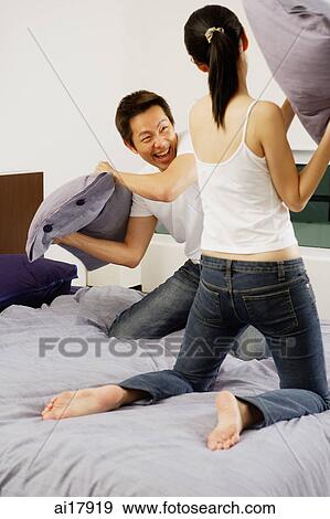 Couple having pillow fight in bedroom View Large Photo Image Stock Photo - Couple having pillow fight in bedroom . Fotosearch