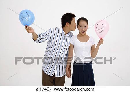 Couple holding balloons, man leaning over to kiss woman on cheek View Large Photo Image Stock Photo - Couple holding balloons, man leaning over to kiss woman on cheek . Fotosearch