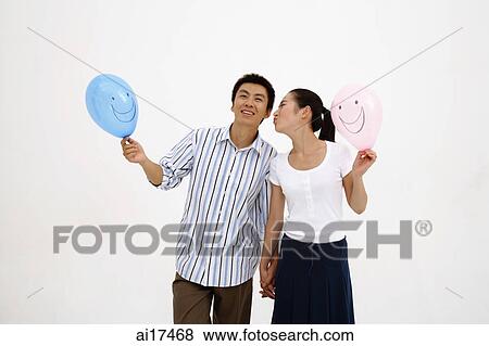 Couple holding hands, holding balloons, woman kissing man on cheek View Large Photo Image Stock Photo - Couple holding hands, holding balloons, woman kissing man on cheek . Fotosearch