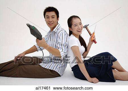 Couple sitting back to back, holding tools View Large Photo Image Stock Image - Couple sitting back to back, holding tools . Fotosearch